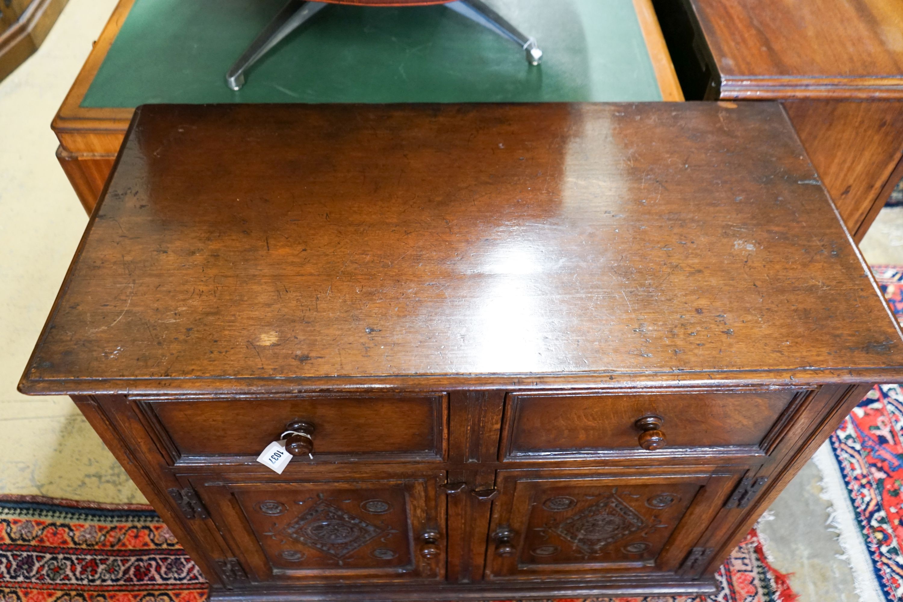 A 17th century style carved and panelled oak cupboard